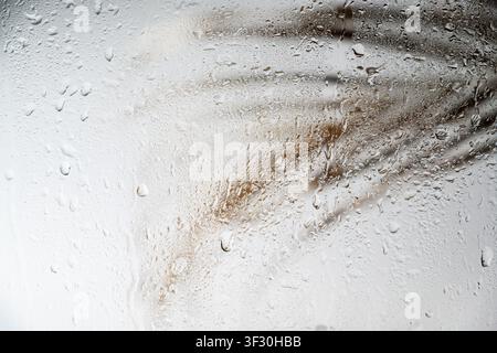 A close-up view of a gray painted surface featuring vertical liquid streaks and drips, creating a grunge industrial background for design projects Stock Photo