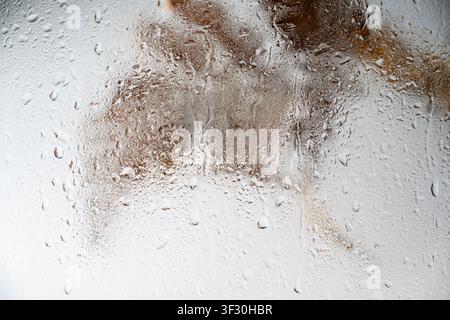 A close-up view of a gray painted surface featuring vertical liquid streaks and drips, creating a grunge industrial background for design projects Stock Photo