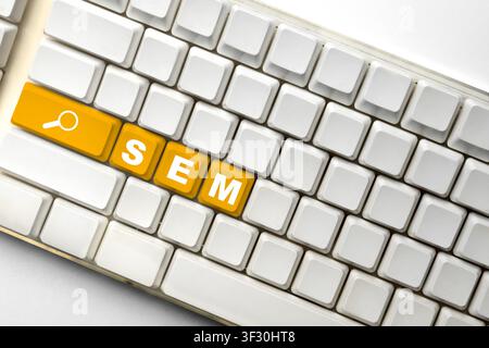 White computer keyboard featuring orange keys spelling out SEM with a search icon, illustrating digital marketing and search engine marketing strategi Stock Photo