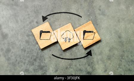 Conceptual image representing cloud computing, data backup, and file synchronization using wooden blocks with icons on a concrete background. Ideal fo Stock Photo