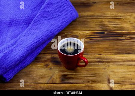Cosy knitted blue sweater and cup of coffee on wooden table. Winter cozy concept Stock Photo