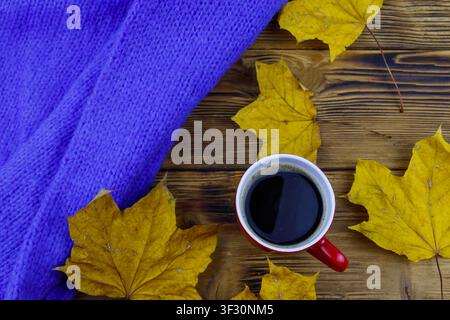 Cosy knitted blue sweater, cup of coffee and autumn maple leaves on wooden table. Top view. Autumn cozy concept Stock Photo