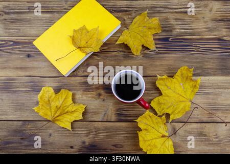 Cup of coffee, book and autumn maple leaves on wooden table. Top view. Autumn cozy concept Stock Photo