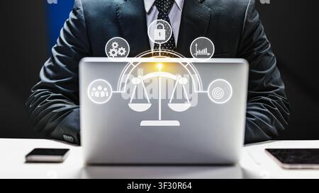 Businessman using a laptop with a glowing digital interface featuring scales of justice and corporate icons. Concept for law, compliance, ethics, and Stock Photo