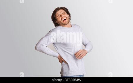 Sharp back pain. Man suffering from pain and screams Stock Photo