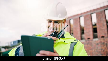 Radio, happy and construction worker on site with tablet for research on building renovation. Man, planning and mature civil engineer with feedback on Stock Photo