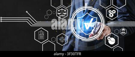 A professional businessman interacts with a futuristic virtual dashboard featuring a glowing shield, checkmark, and icons for law, audit, and manageme Stock Photo
