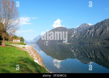The picturesque Lake Idro in the Italian Alps with clear water reflecting the surrounding mountains on a sunny day. Stock Photo