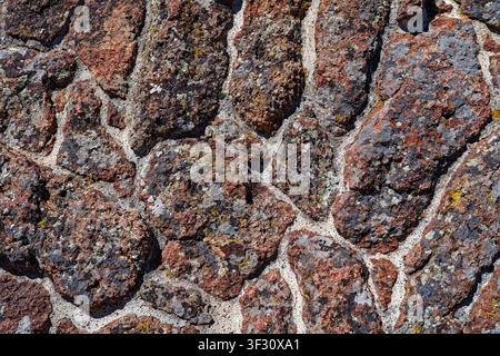 Abstract patterns in lichen covered rocks cemented into an exterior wall Stock Photo