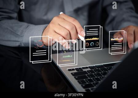 Businessman using laptop and stylus with virtual data document holograms. Concept of digital financial reporting, business analytics, paperless office Stock Photo