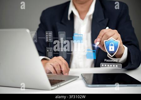 Businessman using laptop and tablet with virtual document folder and password shield hologram. Concept of data security, cybersecurity, corporate file Stock Photo