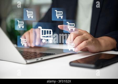 Businessman hand touching virtual screen with shopping cart icons on laptop. Concept of ecommerce, online shopping, digital retail business, internet Stock Photo