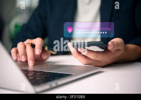 Businessman using smartphone and laptop with cybersecurity shield icon. Concept of two-factor authentication, strong password protection, and secure o Stock Photo