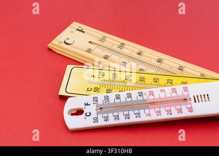 Group of Three Different Thermometers Stacked Together on Red Background Stock Photo