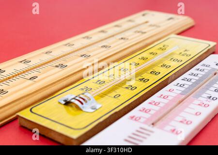 Macro Close-Up Angle of Three Thermometers Lined Up on Red Surface Stock Photo