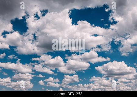 Wide panoramic view of a vivid blue sky filled with scattered white and grey cumulus clouds in bright daylight. Stock Photo