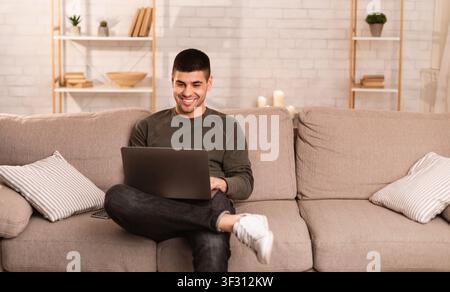 Man using his laptop sitting on sofa Stock Photo