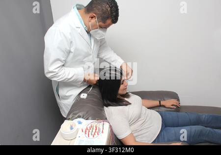 Latin neurologist medical specialist doctor measures the head of his Latin woman patient to stick the electrodes and check the brain activity Stock Photo