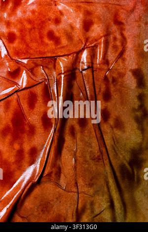 An abstract macro shot of a glossy, burnt orange and brown surface featuring heavy wrinkles, deep creases, and subtle reflections. Ideal for rustic or Stock Photo