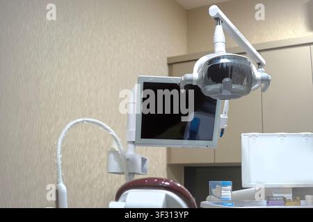 Close-up of advanced dental equipment in a sterile clinic, featuring a professional surgical light, high-resolution monitor, and clinical tools for pa Stock Photo