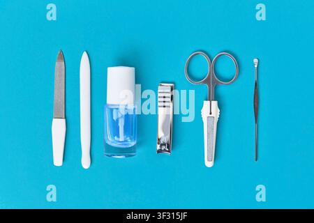 Manicure set and nail polish arranged in a row on blue background Stock Photo
