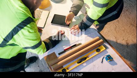 Construction, review or hands on site with blueprint, project discussion or insight on building layout. Above, people or architect with tech Stock Photo
