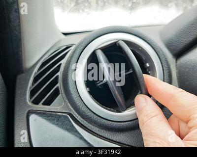 Person adjusts car air vent to control air flow while getting ready for a trip in cold weather. Adventure awaits on the road. Stock Photo