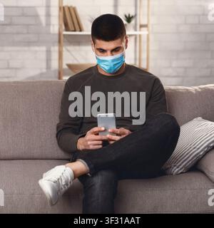 Man wearing surgical mask using smart phone Stock Photo