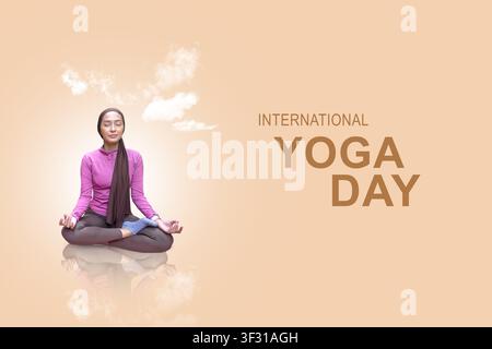 A young Indonesian southeast asian muslim woman in modest activewear and a headscarf sits in a meditative yoga pose against a soft peach background wi Stock Photo