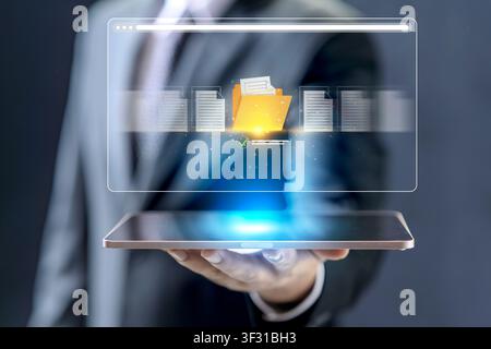A professional businessman uses a tablet to access and organize digital files and folders through a glowing cloud-based interface, representing modern Stock Photo