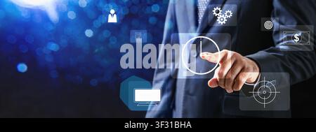 Businessman in a suit interacting with a virtual dashboard of icons representing time, finance, strategy, and operations on a glowing blue bokeh backg Stock Photo