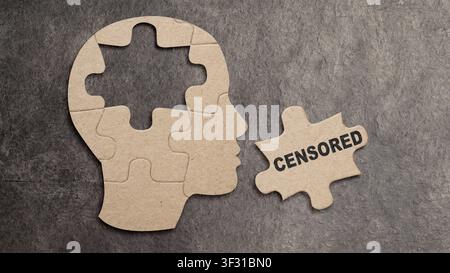 Conceptual image of a jigsaw puzzle in the shape of a human profile with a central piece removed and labeled CENSORED, representing memory loss, suppr Stock Photo