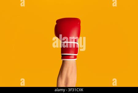 Sportsman wearing boxing glove over orange background, closeup of hand Stock Photo
