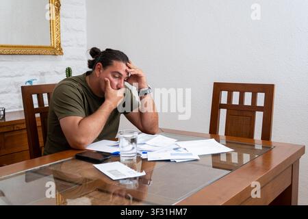 Man looking stressed and worried while reviewing many financial documents and invoices Stock Photo