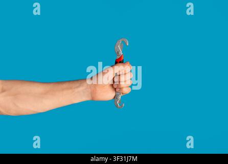 Unrecognizable man holding universal spanner over blue background, blank space Stock Photo