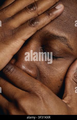 Black Man Covering Face Expressing Stress and Mental Fatigue Stock Photo