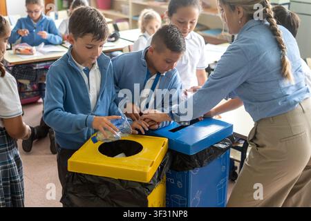 Elementary School Students Learning to Recycle Plastic Bottles with Teacher in Classroom Stock Photo