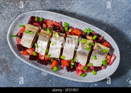 Herring salad with beetroot and vegetables classic Russian appetizer. Top view of dish on plate garnished with green onions. Stock Photo