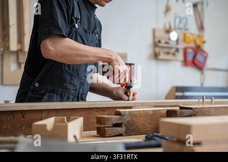 Craftsman technician working in restoration workshop, using professional cordless impact driver tool Stock Photo