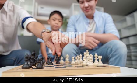 Asian multigenerational family playing chess at home for strategic learning Stock Photo