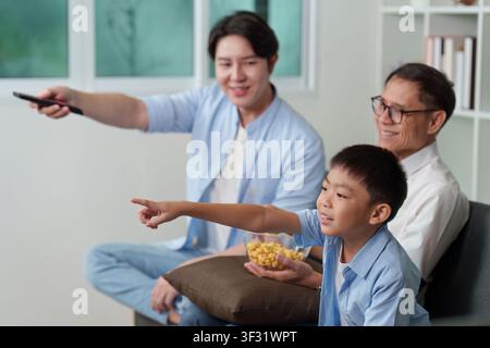 Multigenerational Asian family watching television together at home Stock Photo