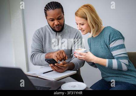 Diverse colleagues collaborating, discussing content on a smartphone Stock Photo