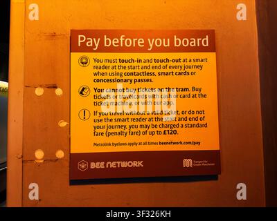 Manchester, UK - May 07, 2026: Yellow Pay before you board sign on a Metrolink tram platform explaining ticket and touch in rules. Stock Photo