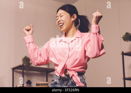 Happy Young Asian Woman Dancing Joyfully In Modern Room, Lifestyle Concept Stock Photo
