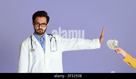 No to corruption. Serious Indian doctor refusing bribe from female patient on lilac background, panorama Stock Photo