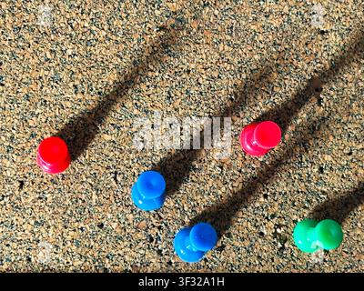 Coloured push pins in a cork board. Long shadows Stock Photo