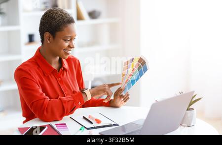 Woman Selecting Color Samples While Working at a Desk in a Bright Room Stock Photo