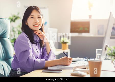 Smiling Young Asian Woman Working At Home Office, Taking Notes, Business Concept Stock Photo