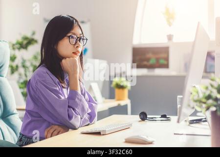 Focused Asian Woman In Eyeglasses Working At Desk In Modern Office, Business Concept Stock Photo