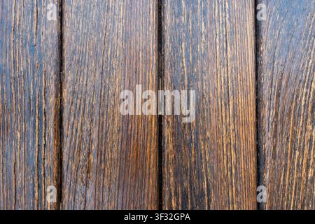 Close-up of weathered brown wooden planks with pronounced grain, grooves and dark gaps forming a rustic background. Stock Photo